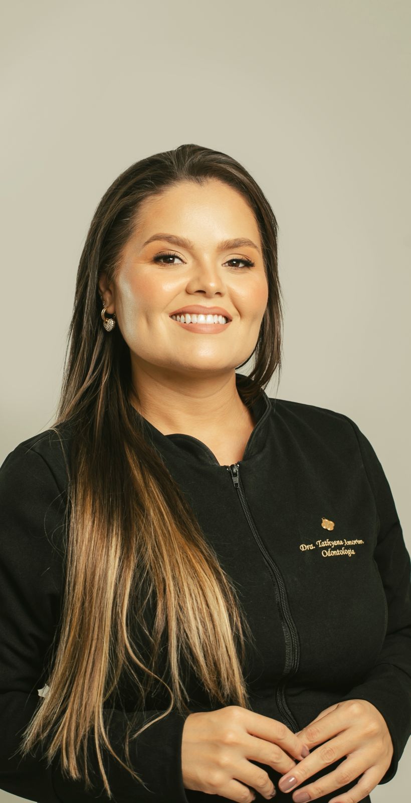 Dra. Tathyane Amorim de jaleco preto bordado